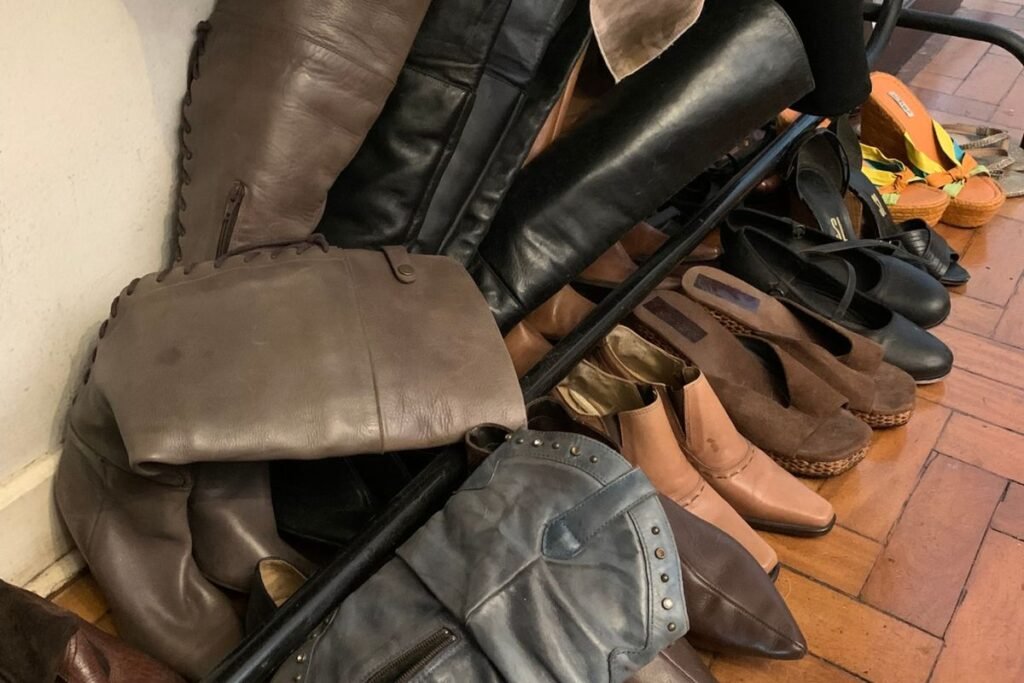 Fileira de sapatos à venda, com botas e tamancos no brechó o Legado da Vó